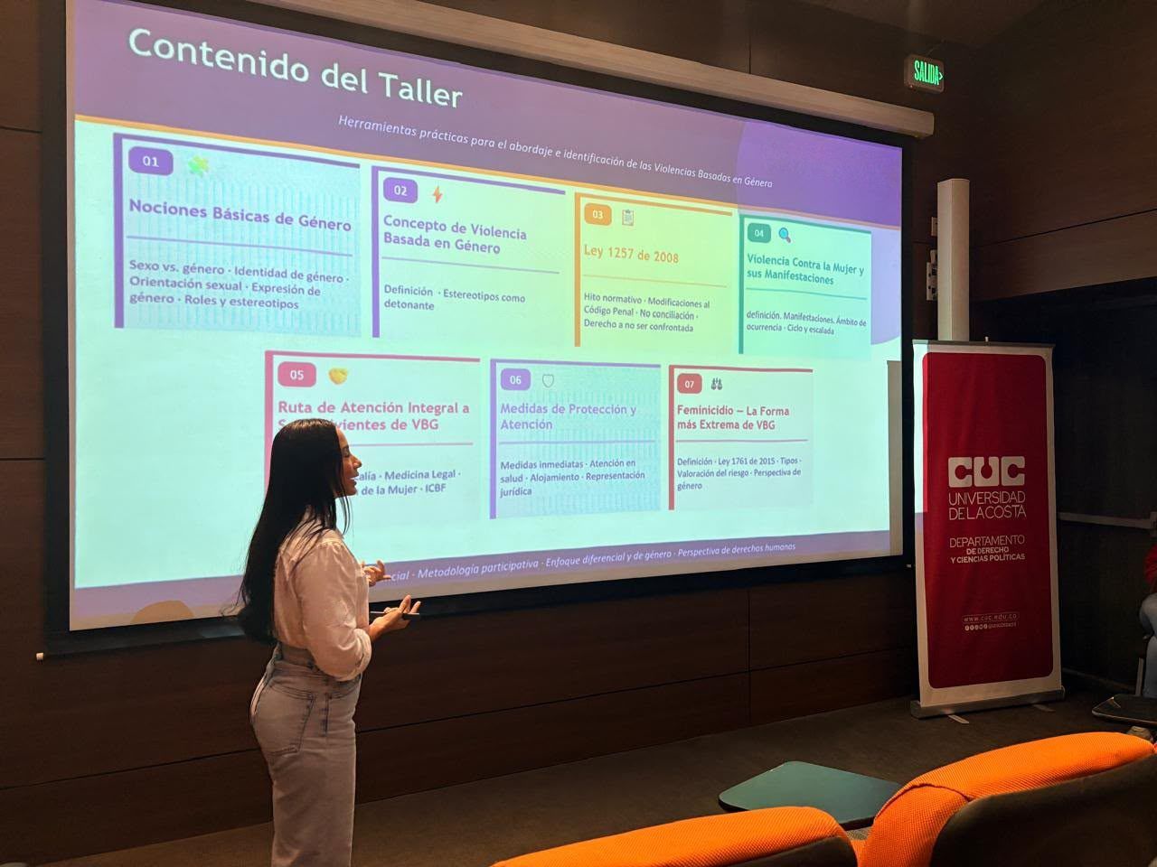 Una facilitadora presenta el contenido de un taller sobre violencias basadas en género en un auditorio de la Universidad de la Costa.